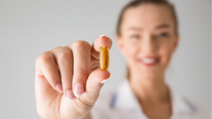 Woman holding up a vitamin pill