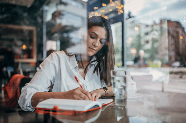 Woman writing book in coffee shop